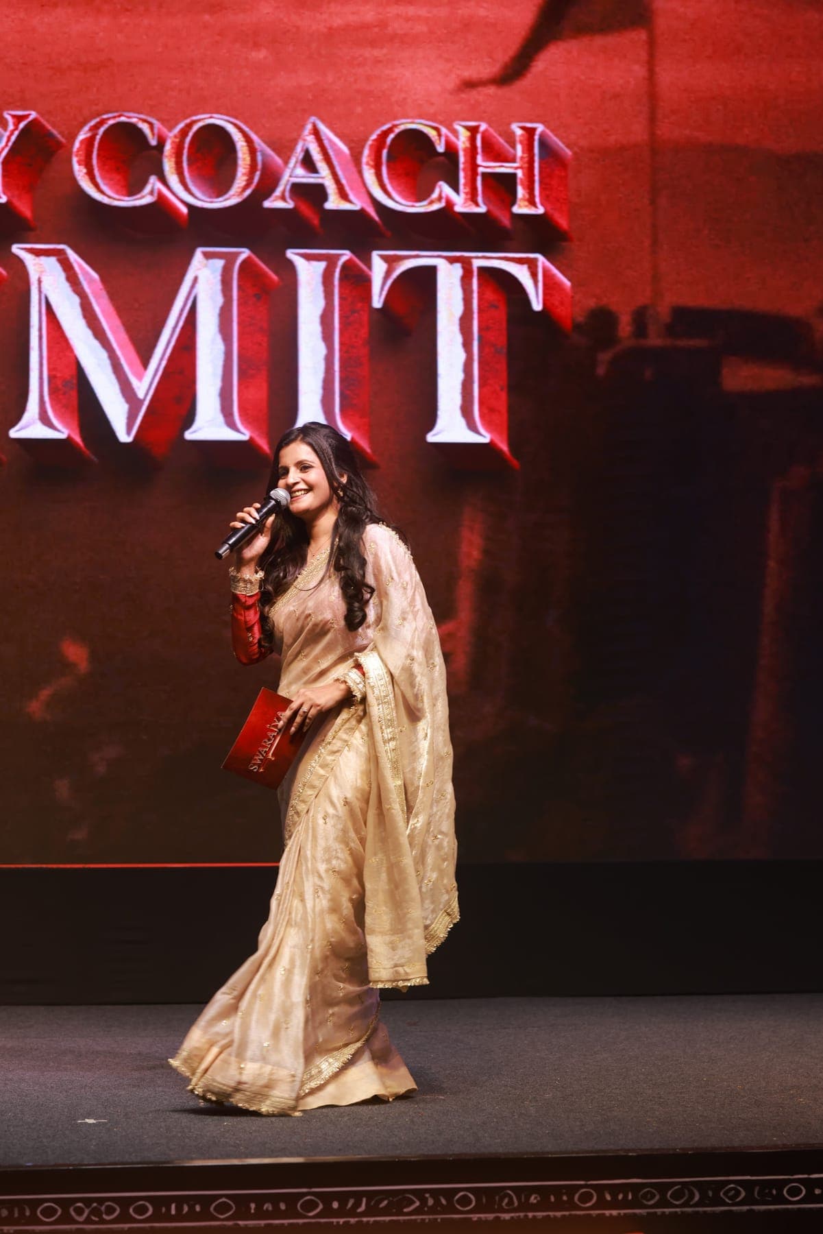 Tripti speaking on stage at the Wealthy Coach Summit